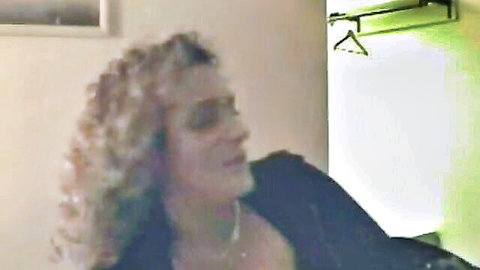 Jenna with curly blonde hair in dark jacket, begging at glory hole