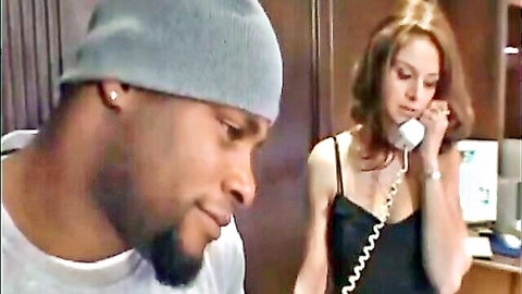 Black mechanic in beanie watches brunette woman on phone in shop