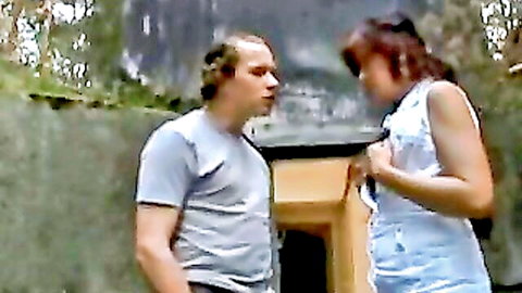 Mature redhead in white tank top close to balding man outdoors