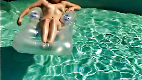 Petite nude brunette with small tits spreads legs on pool float exposing shaved pussy