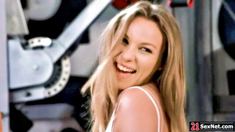 Smiling blonde in white tank top at gym, teasing threesome vibe