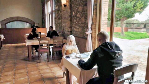Sexy blonde in low-cut dress teased by man at restaurant table
