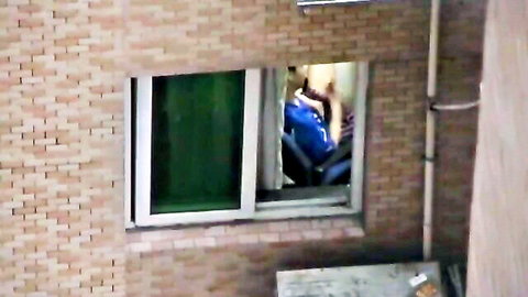 Blurry voyeur shot of Asian guy sitting legs spread in blue shorts through window