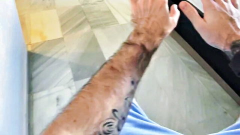 Max Dennison's hairy tattooed arm holding phone in blue shirt