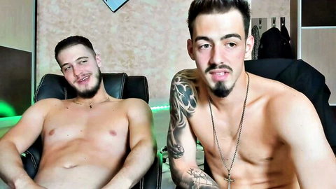 Two muscular shirtless gay hunks with tattoos smiling teasingly on webcam