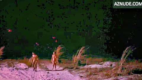 Nude couple walking through misty marsh at night with glowing red lights in Motel Destino