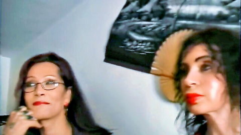 Two seductive trans women with dark hair and red lips in intimate anal adventure scene