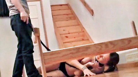 Blindfolded teen in black lingerie lies exposed on floor near staircase with standing man