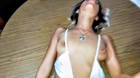 Petite Latina teen's hard nipples visible through sheer white lace bra lying on wooden table head tilted back