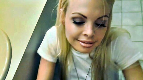 Jesse Jane smiling in white tank top, blonde beauty in bathroom BTS