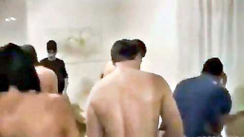 Blurry group of nude men and women backs in gangbang room setup