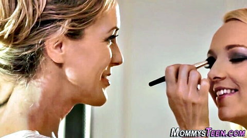 Blonde MILF intimately applies makeup brush to teen girl's eye smiling closeup
