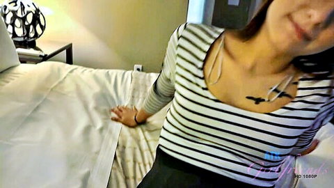 Jaye Summers smiling in striped top with chest tattoo, seductive bedroom pose