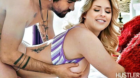 Tattooed hunk gropes blonde babe's perky tits from behind on bed