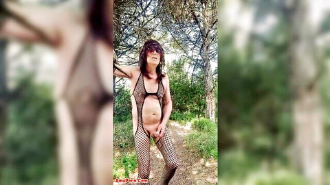 Pamela in sheer fishnet bodysuit posing outdoors in pine forest