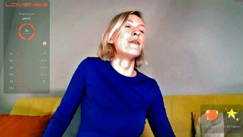 Blonde amateur Chaturbate cam girl in blue top, seductive open-mouth expression