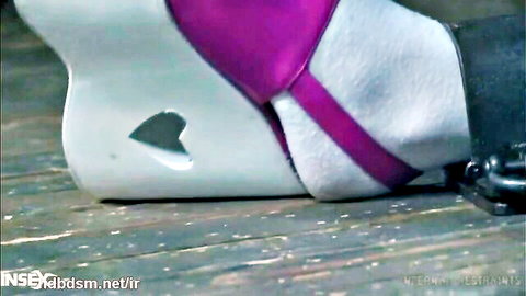 Close-up of sexy white high-heel boot with purple straps and heart cutout on petite foot over wooden floor