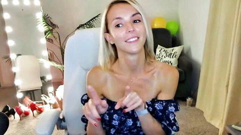 Blonde cam model Martha Mayer smiling in off-shoulder floral top, teasing cleavage
