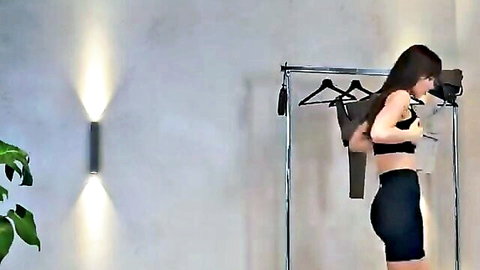 Fit Asian woman in black sports bra and shorts, side profile try-on pose