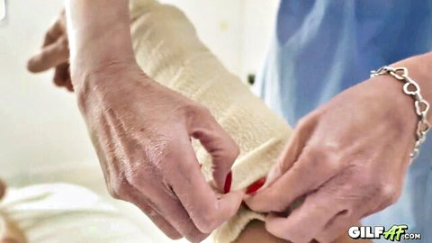 56-year-old GILF nurse in uniform adjusting bandage on patient's arm