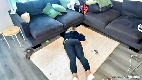 Blonde girl in black leggings lying face down on floor, solo fart fetish scene