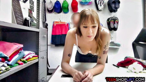 Blonde tattooed shoplifter leaning forward in tight top during security sex scene