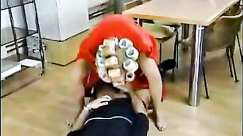 Mature woman in red dress with curlers facesitting man on floor