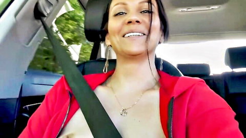 Smiling brunette MILF flashes medium tits through open red hoodie in car with seatbelt