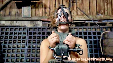 Sasha bound in metal BDSM restraints and gag, topless submission