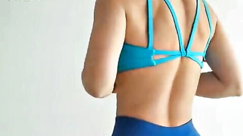 Sexy fit woman in tight teal yoga pants and crisscross sports bra showing juicy ass from behind