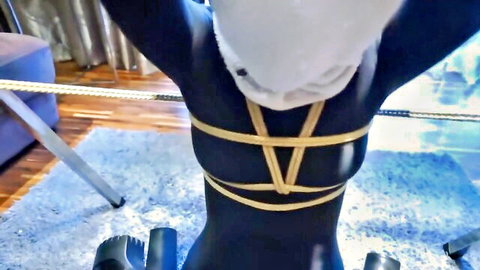 Zentai suited woman in yellow rope bondage harness, arms raised