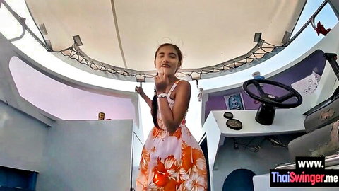 Petite Thai teen in floral dress posing playfully on boat deck