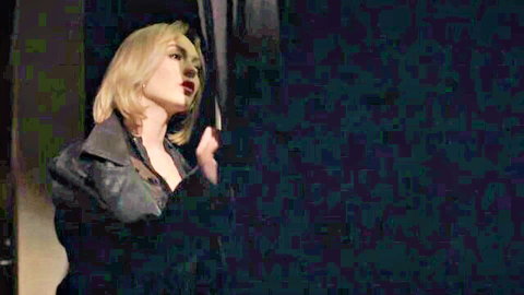 Seductive blonde in black leather jacket poses with sultry pout against dark backdrop