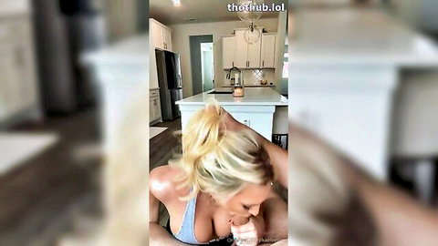 Busty blonde in tight blue top showing huge cleavage leaning over kitchen counter