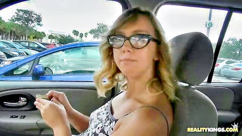 Blonde with glasses teases deep cleavage in lacy top while sitting in public parking lot car