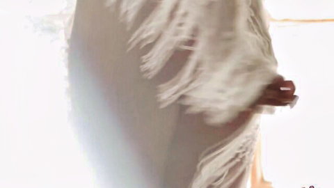 Jenna Foxx in flowing white fringed dress, sensual beach pose