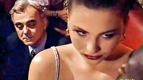 Italian club gangbang scene with brunette in white dress surrounded by suited men