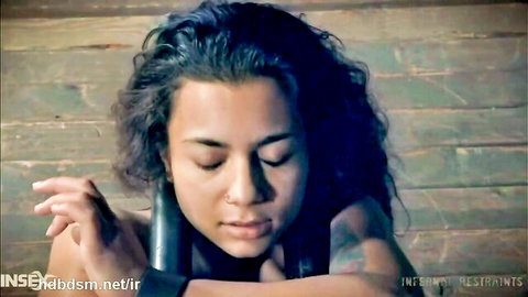 Brunette teen in tight restraints, eyes closed in submission, tattoos visible for brutal anal toy scene