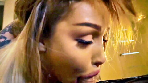 Close-up of sultry blonde Asian woman with intense gaze and parted lips in xxx scene