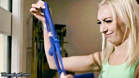 Blonde stepmom smiling while holding blue panties in playful tease