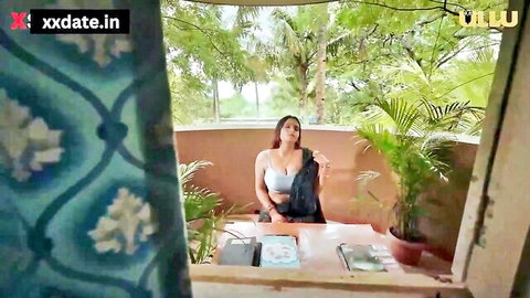 Seductive Indian MILF in blue blouse on balcony, teasing erotic vibe