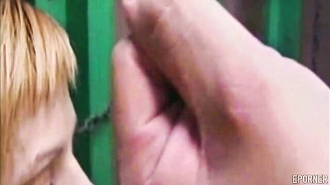 Blonde's pale hand gripping green prison bars intensely in BDSM slave tease