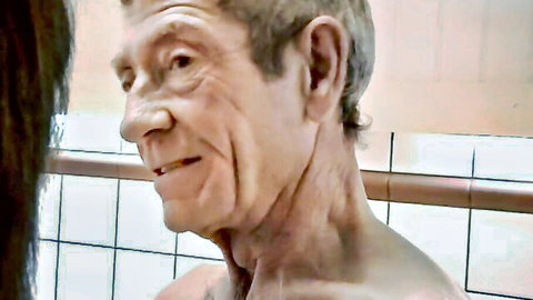 Mature man smiling in shower with long-haired woman, nude close-up