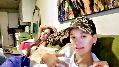 Angelia01m and friend lounging seductively on couch in Chaturbate cam show