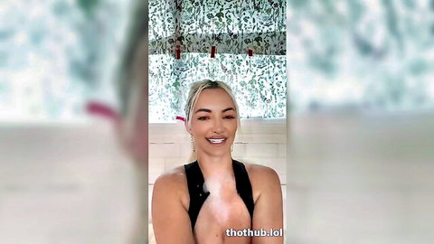 Lindsey Pelas wet blonde bombshell smiling in low-cut black top