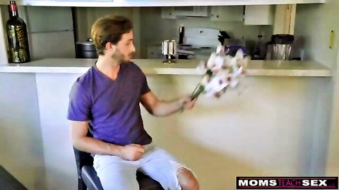 Handsome guy in purple shirt and white shorts holds bouquet of flowers in kitchen Moms Teach Sex taboo tease