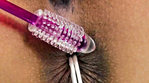 Close-up of thick ribbed purple dildo penetrating wet Asian pussy with white strings dangling.