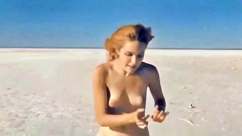 Naked redhead teen walking nude on sunny beach, covering body