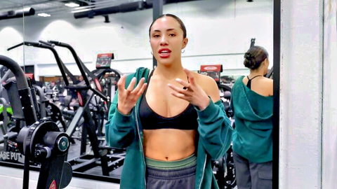 Fit mixed-race woman in sports bra vlogging gym upper body workout