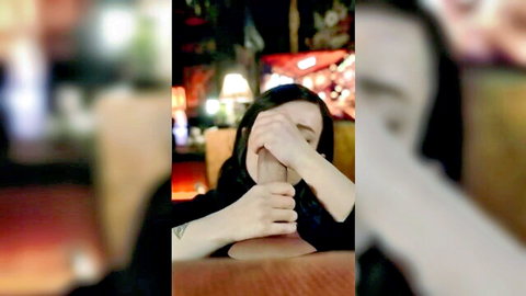 Goth girl covers eyes while teasing blowjob on fleshlight cock toy in dim neon club